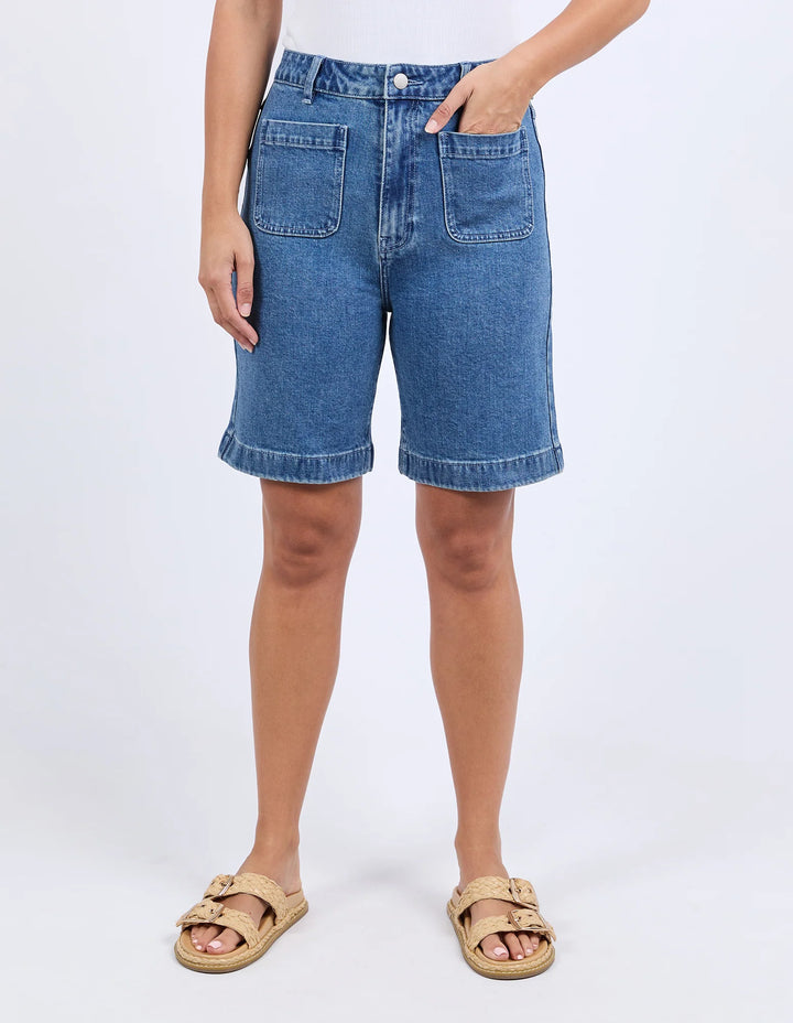 Person wearing blue denim shorts on a white background