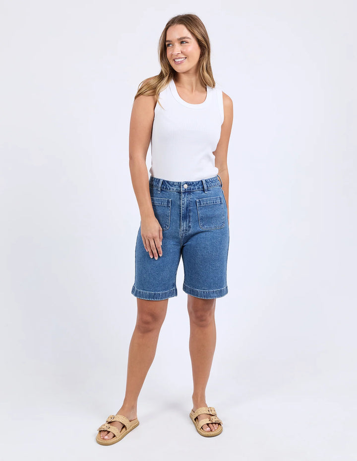 Woman wearing a white tank top and blue denim shorts on a white background
