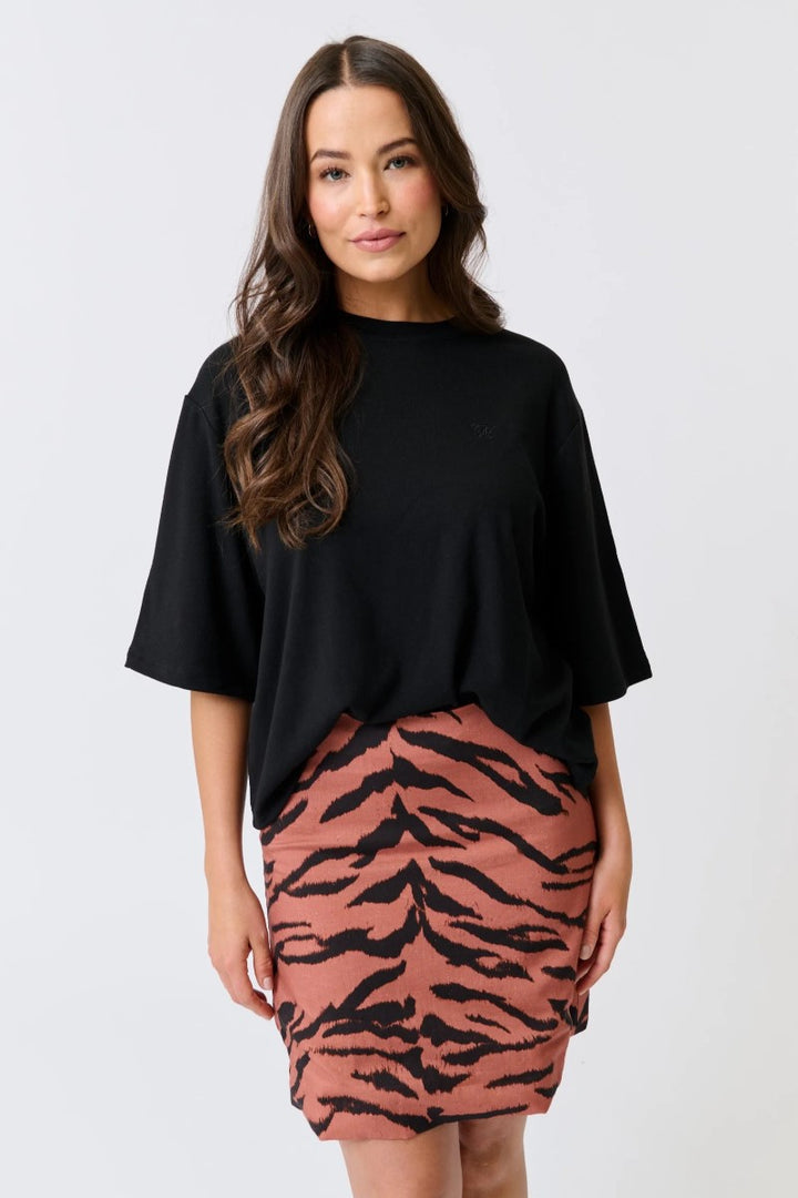 Woman wearing a black top and pink skirt with tiger pattern on a white background