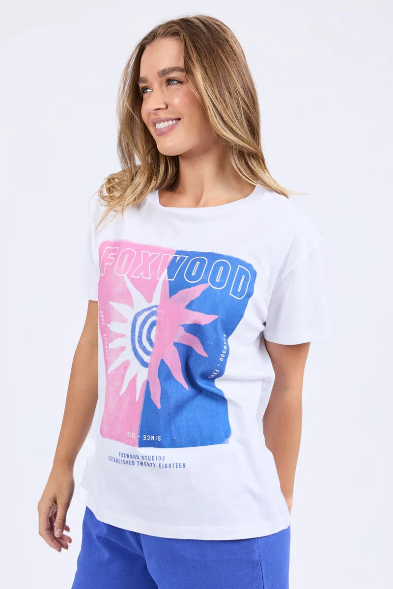 Woman wearing a white t-shirt with colorful graphics on a plain background