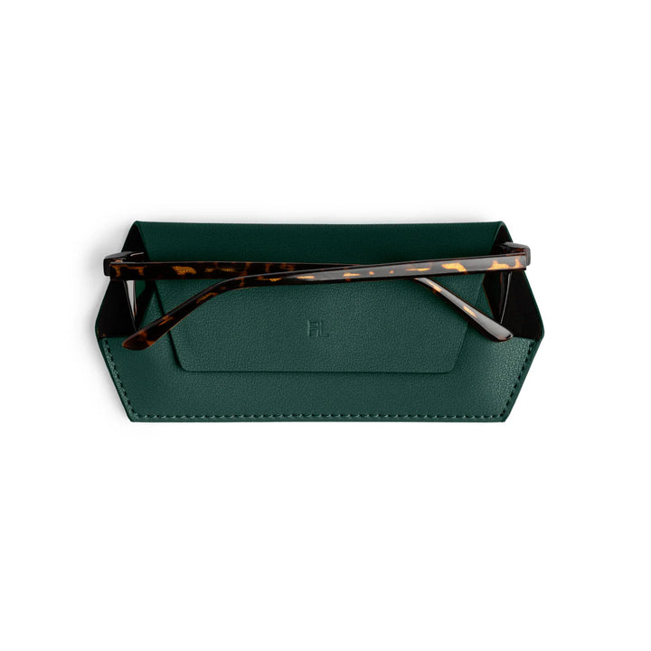 Green leather sunglasses case with tortoiseshell sunglasses on a white background