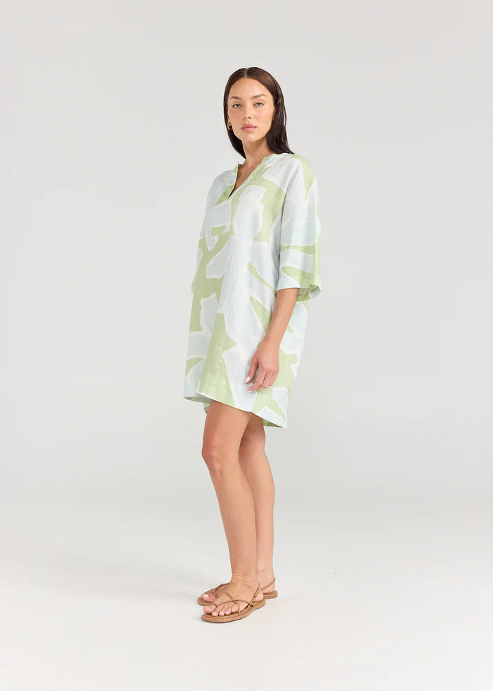 Woman wearing a light green dress with a pattern on a white background