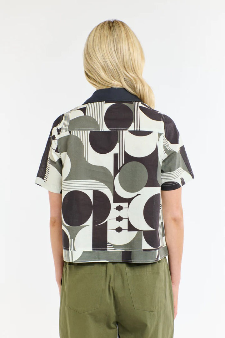 Person wearing a patterned shirt with geometric design on a white background