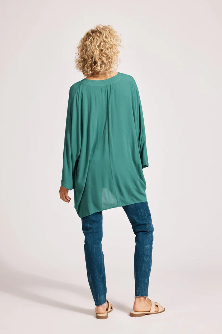 Person wearing a teal oversized t-shirt and blue jeans on a light background