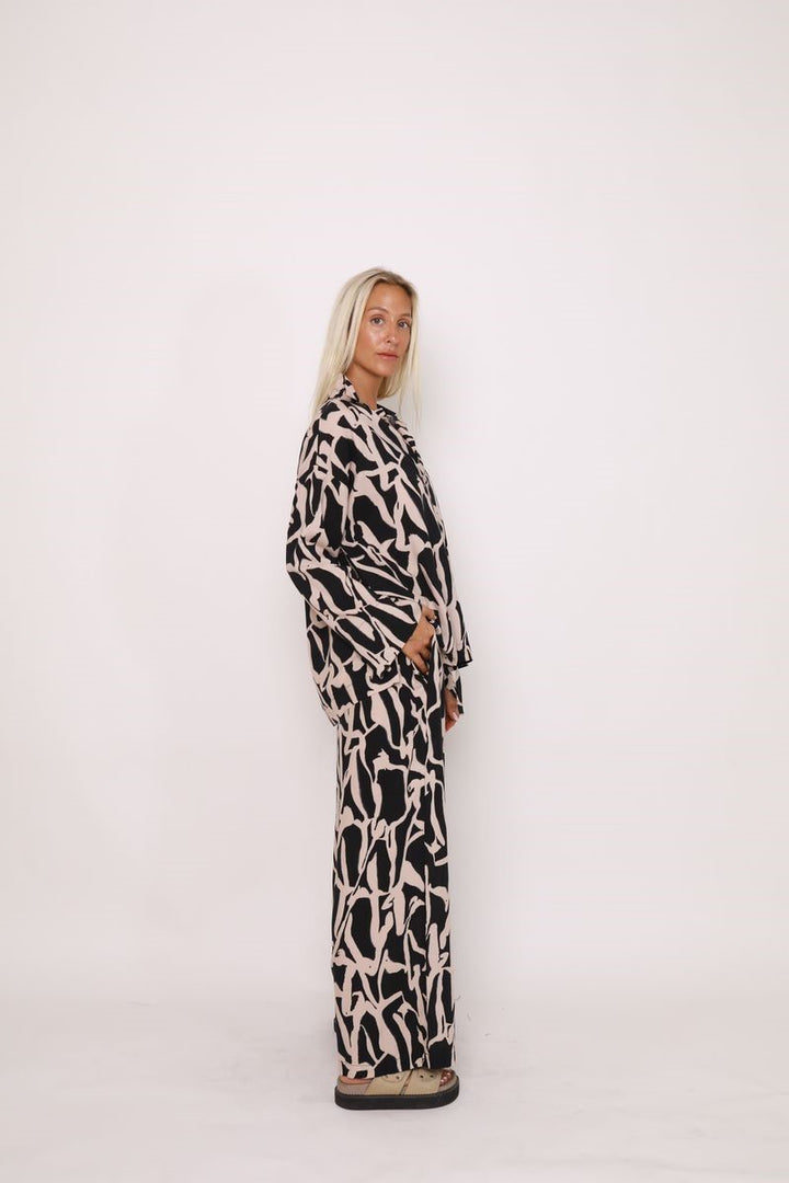 Side view of the Alex Pant in Black Cinnamon from Ivy Vibe, highlighting the wide-leg silhouette, high waist, and flowy fabric for a flattering drape.