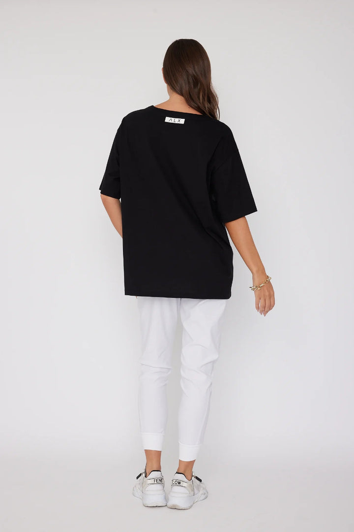 Person wearing a black oversized t-shirt and white pants on a white background