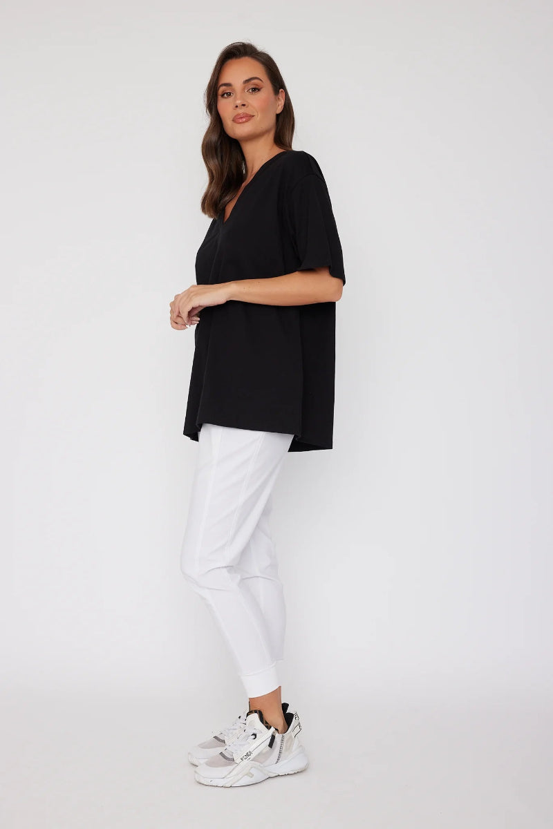 Woman wearing a black top and white pants on a white background