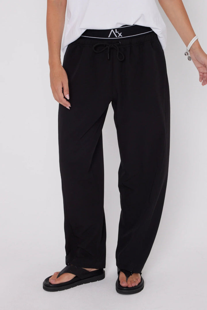 Person wearing black pants with a brand logo on a white background