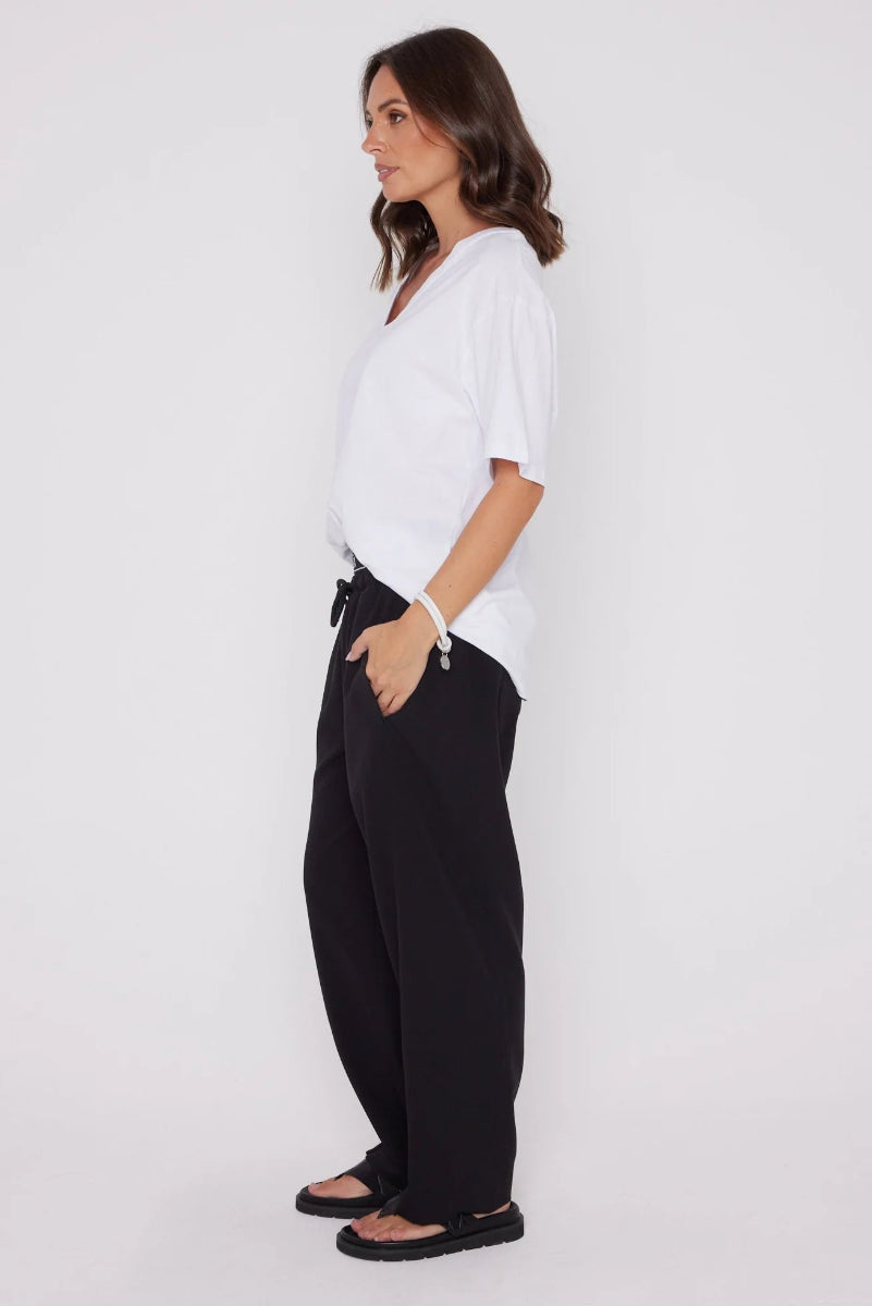 Woman wearing a white top and black pants on a white background