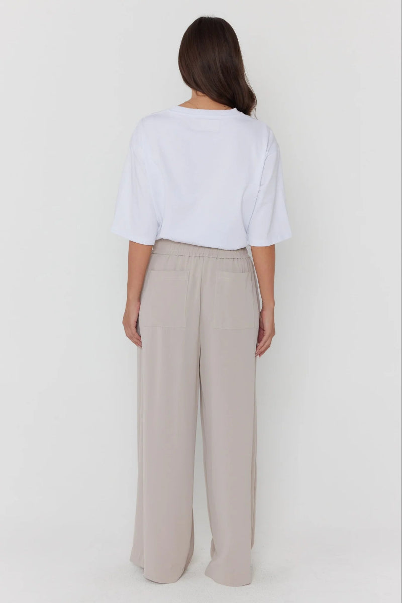 Person wearing a white top and beige pants on a plain background