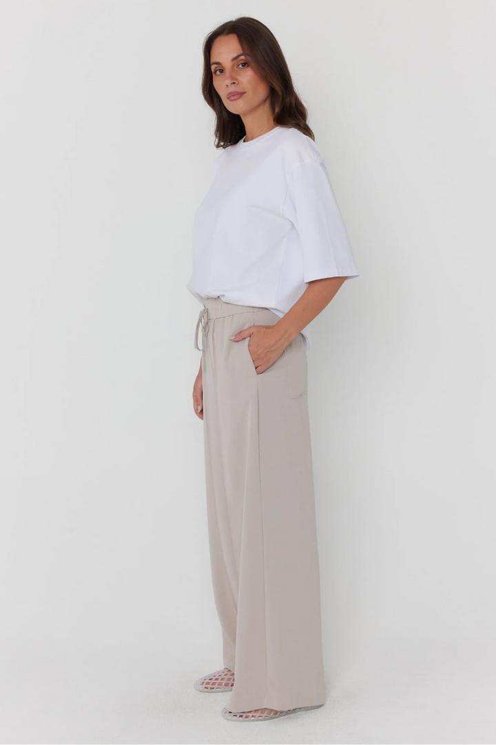 Woman wearing a white top and beige pants on a white background