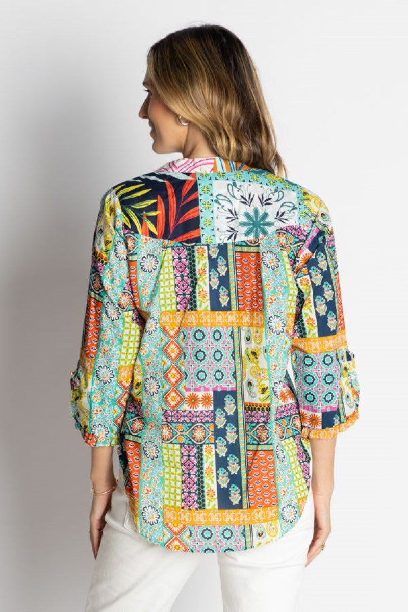 Woman wearing a colorful patchwork blouse against a plain background