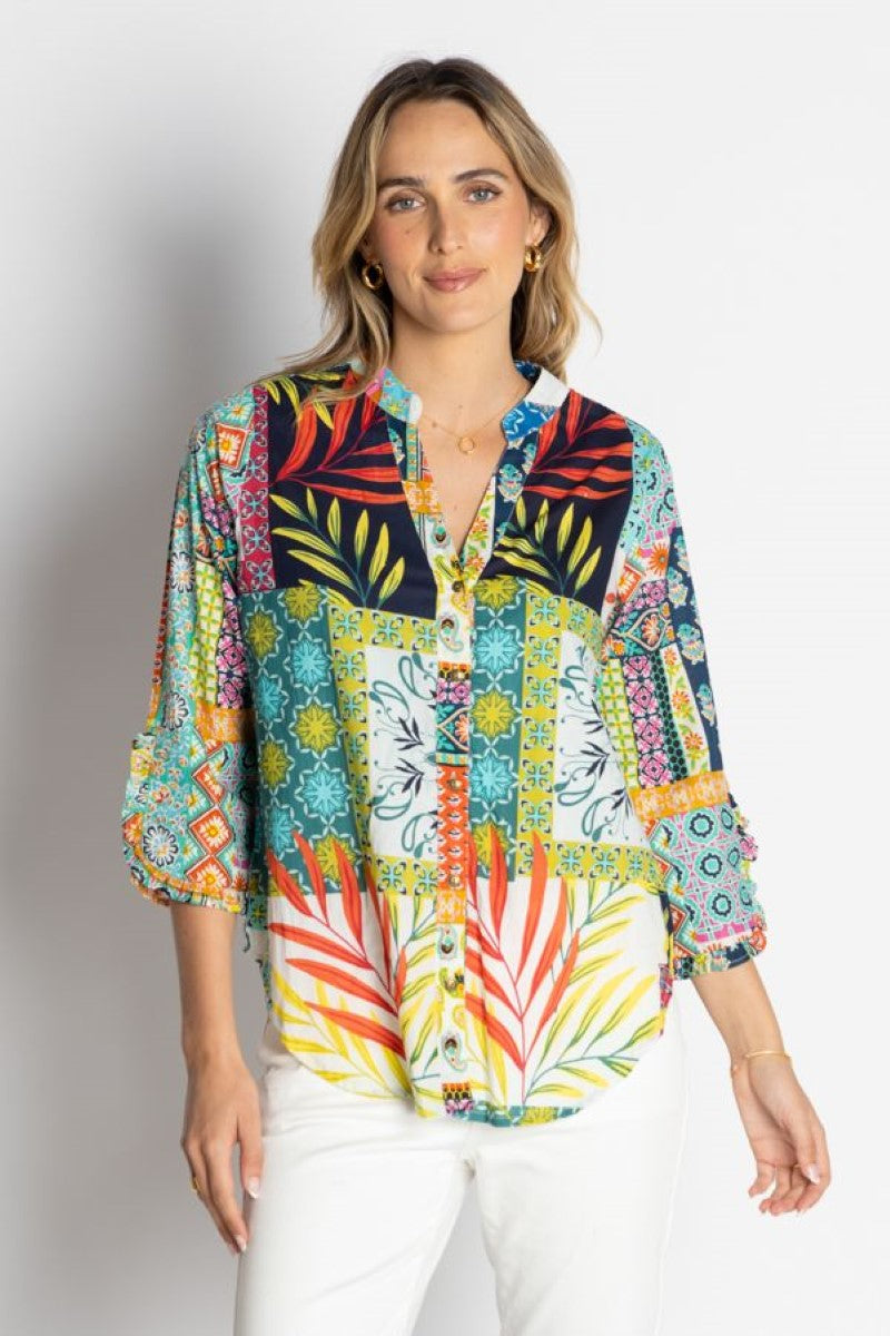 Woman wearing a colorful patterned blouse against a white background