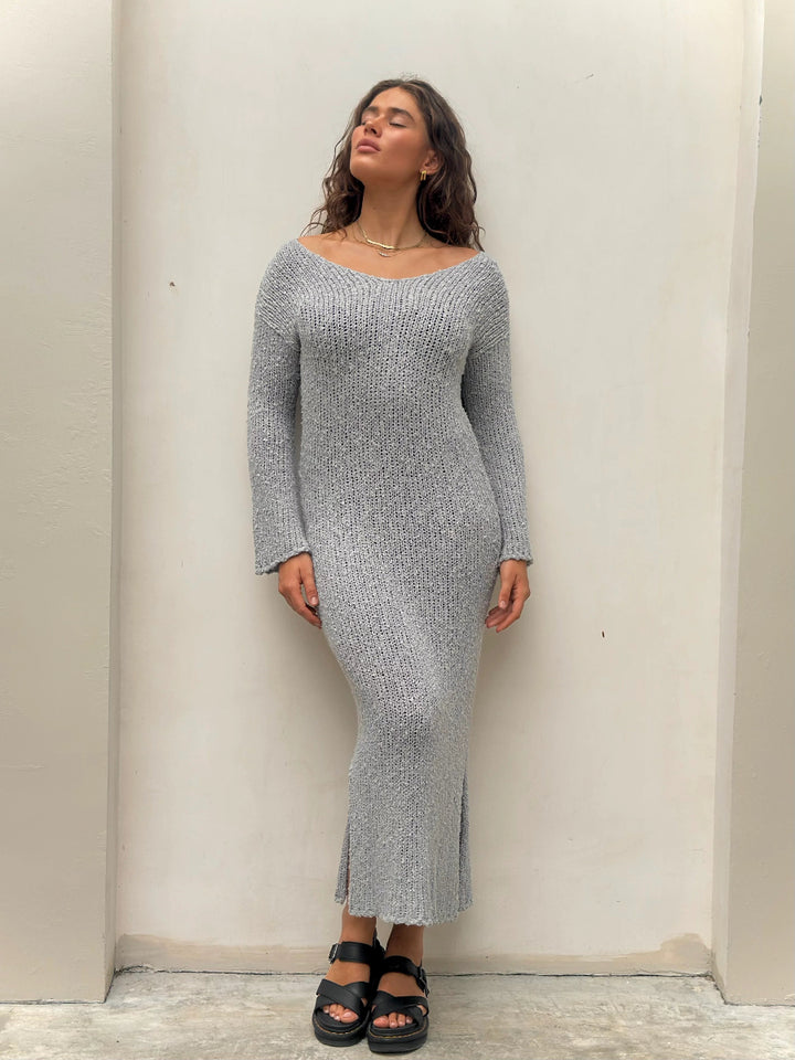 Woman standing in gray knit long-sleeve midi dress.