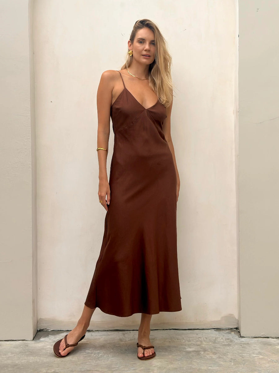 Woman in brown satin slip midi dress with thin straps.