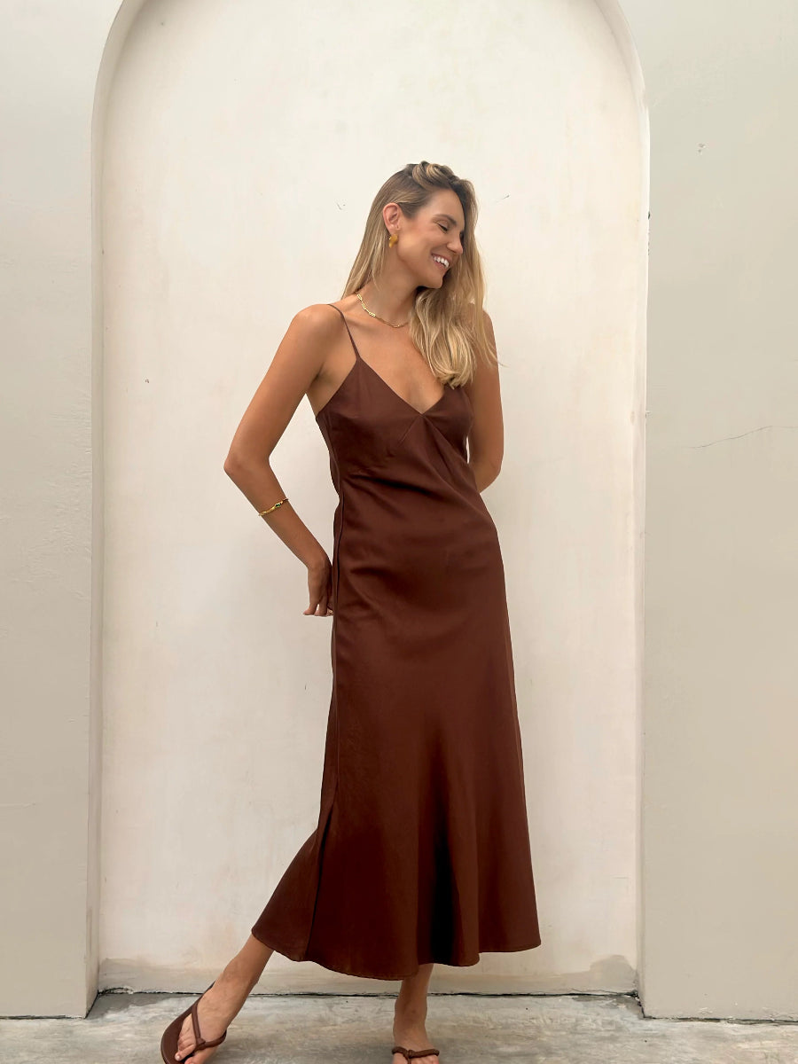 Woman smiling in brown satin slip dress and sandals.