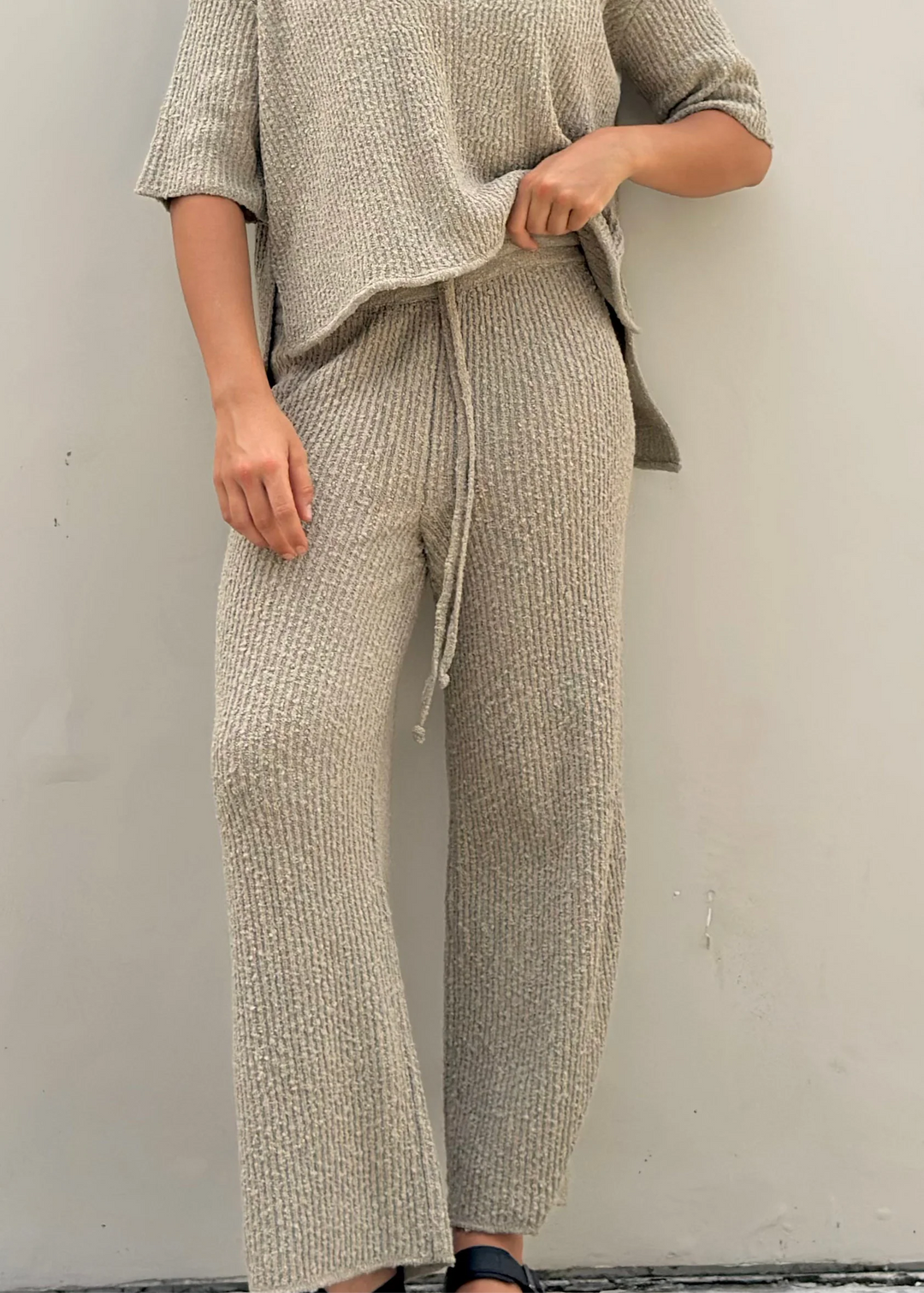 Close-up of beige knit wide-leg pants and drawstring waist.