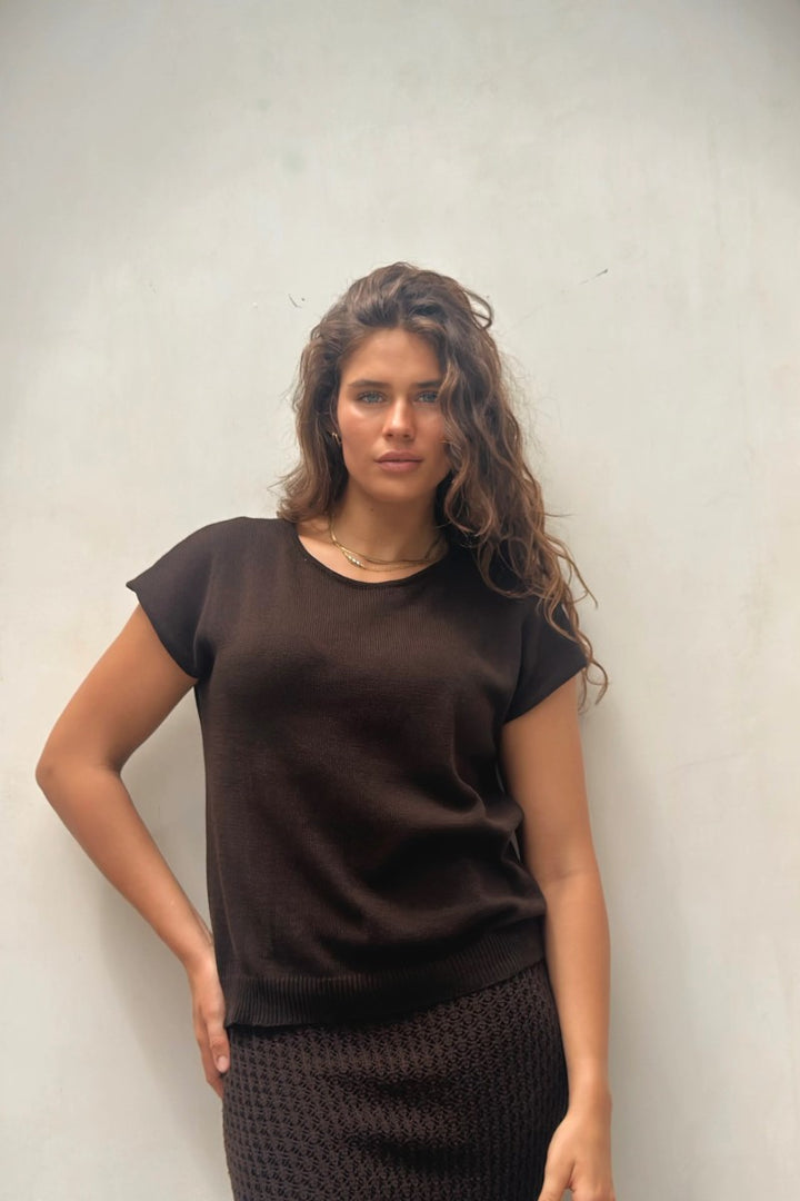 Woman wearing a brown top against a plain background