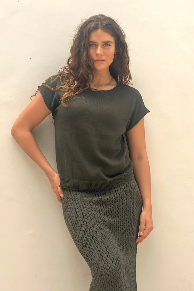 Woman wearing a green outfit against a white wall