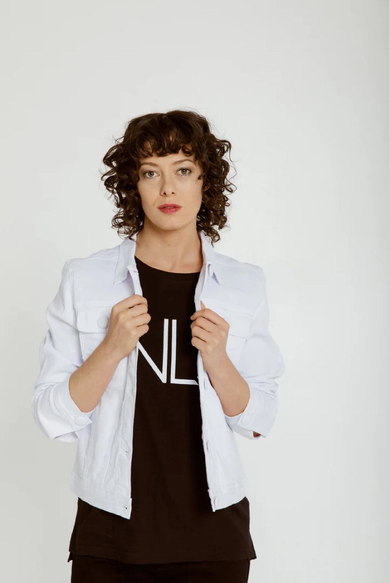 Person wearing a white jacket over a black outfit with a visible brand logo on a plain background