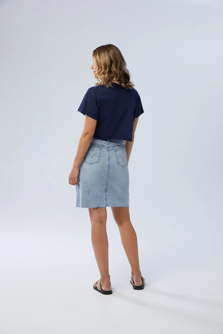 Person wearing a navy t-shirt and light blue denim skirt on a white background
