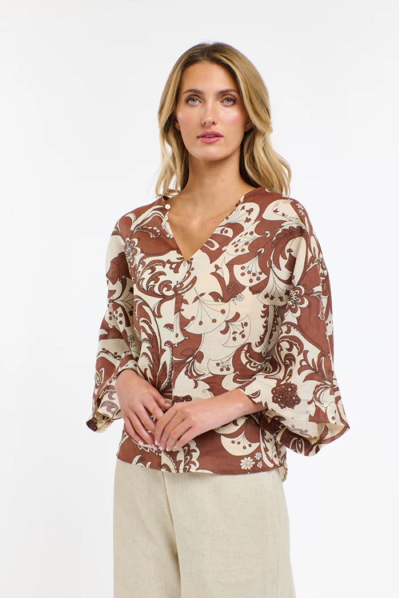 Woman wearing a patterned blouse with a plain background