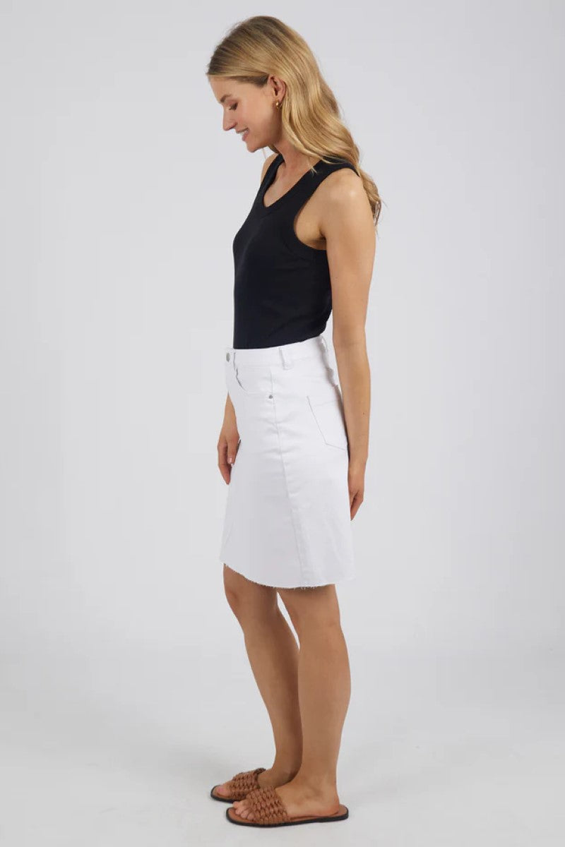 This side view of the Belle Denim Skirt in Cloud Wash showcases its flattering A-line silhouette, soft faded denim, and clean seam detailing for a timeless look.
