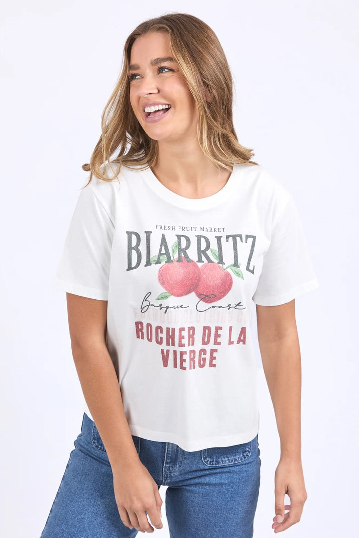 Woman wearing a white t-shirt with text and graphics on a plain background