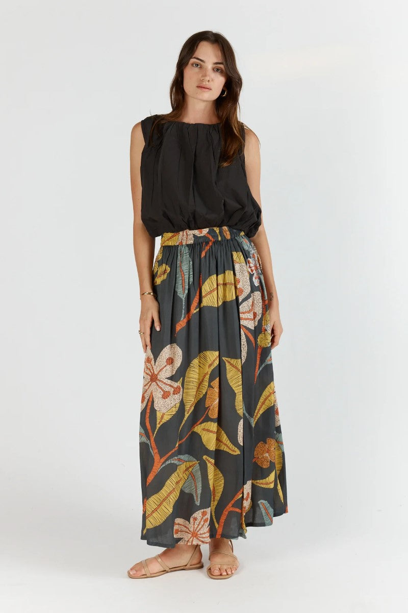 Woman wearing a black sleeveless top and floral skirt on a white background