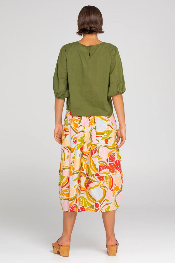 Woman wearing a green top and colorful skirt on a white background