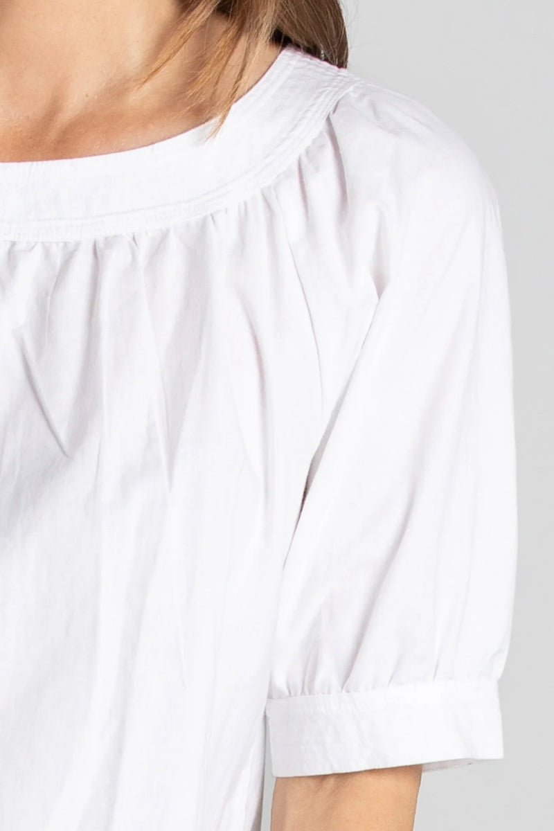 White blouse with rolled-up sleeves on a plain background