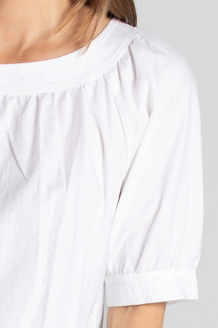 White blouse with rolled-up sleeves on a plain background
