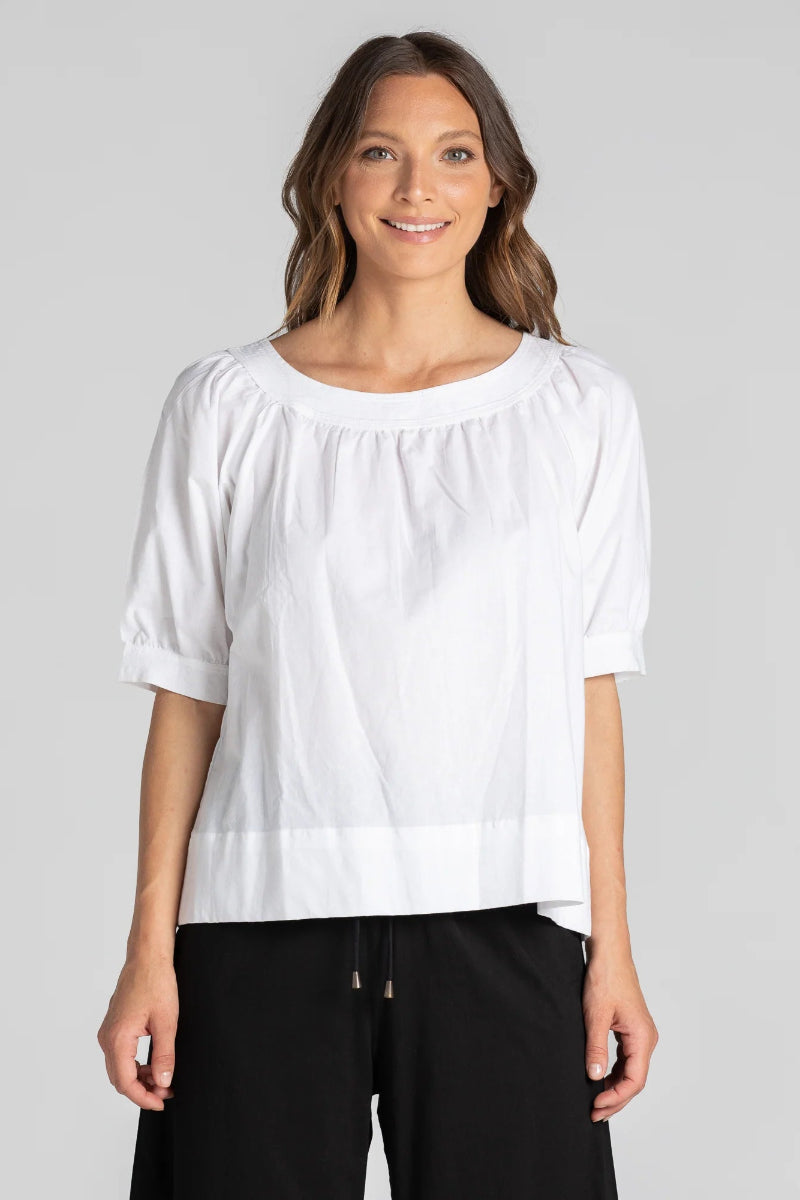 Woman wearing a white blouse and black pants on a gray background