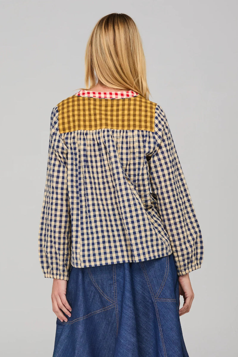 Person wearing a checkered shirt with a yellow collar on a gray background