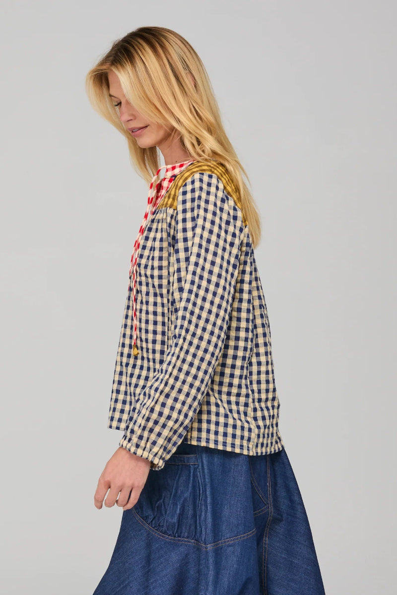 Woman wearing a checkered shirt and denim skirt on a plain background