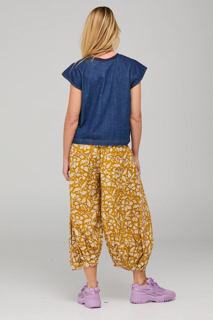 Person wearing a blue top and yellow patterned pants on a gray background