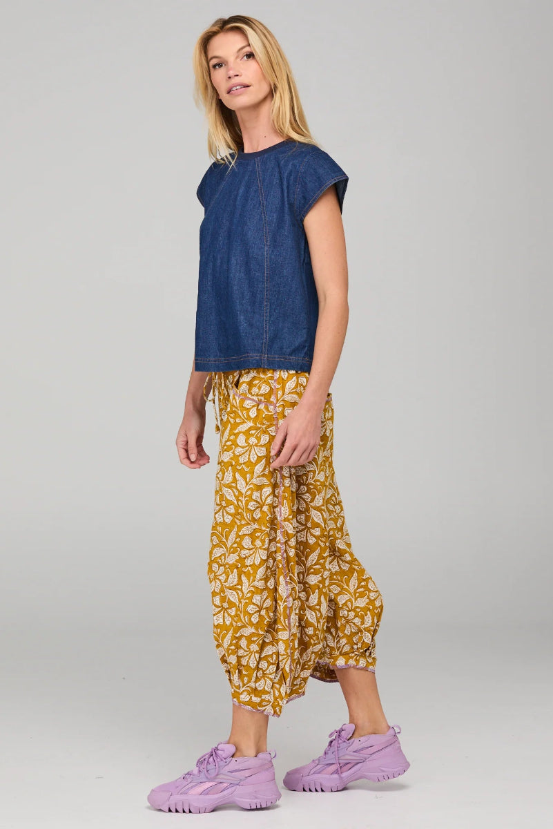 Woman wearing a blue top and yellow patterned pants on a gray background