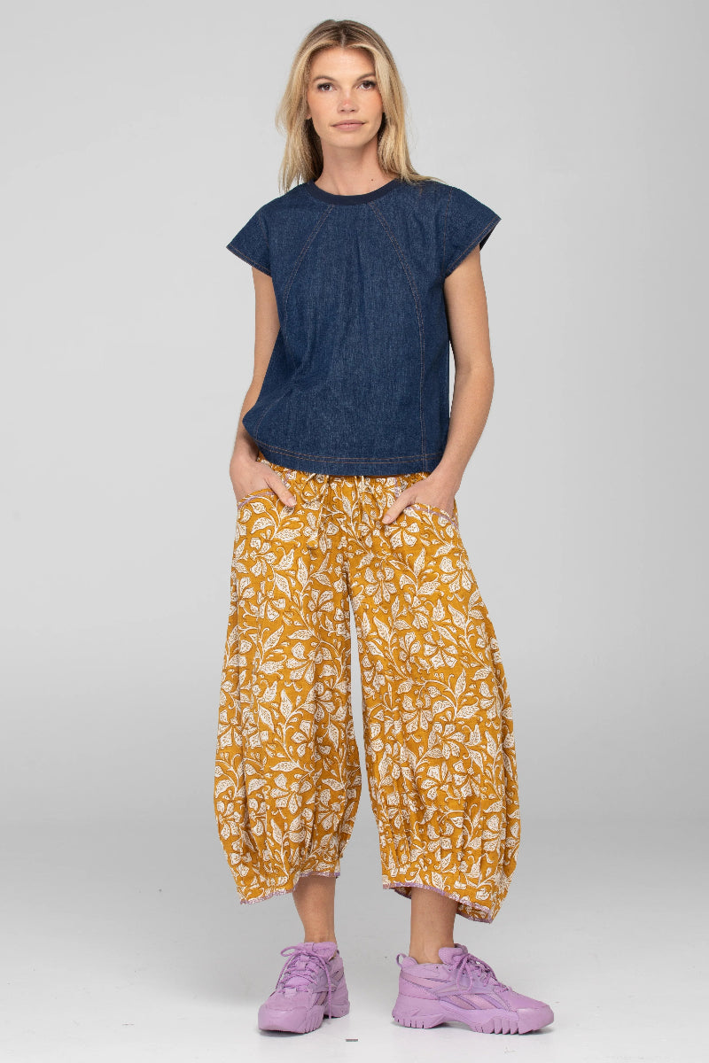 Woman wearing a blue top and yellow patterned pants on a white background