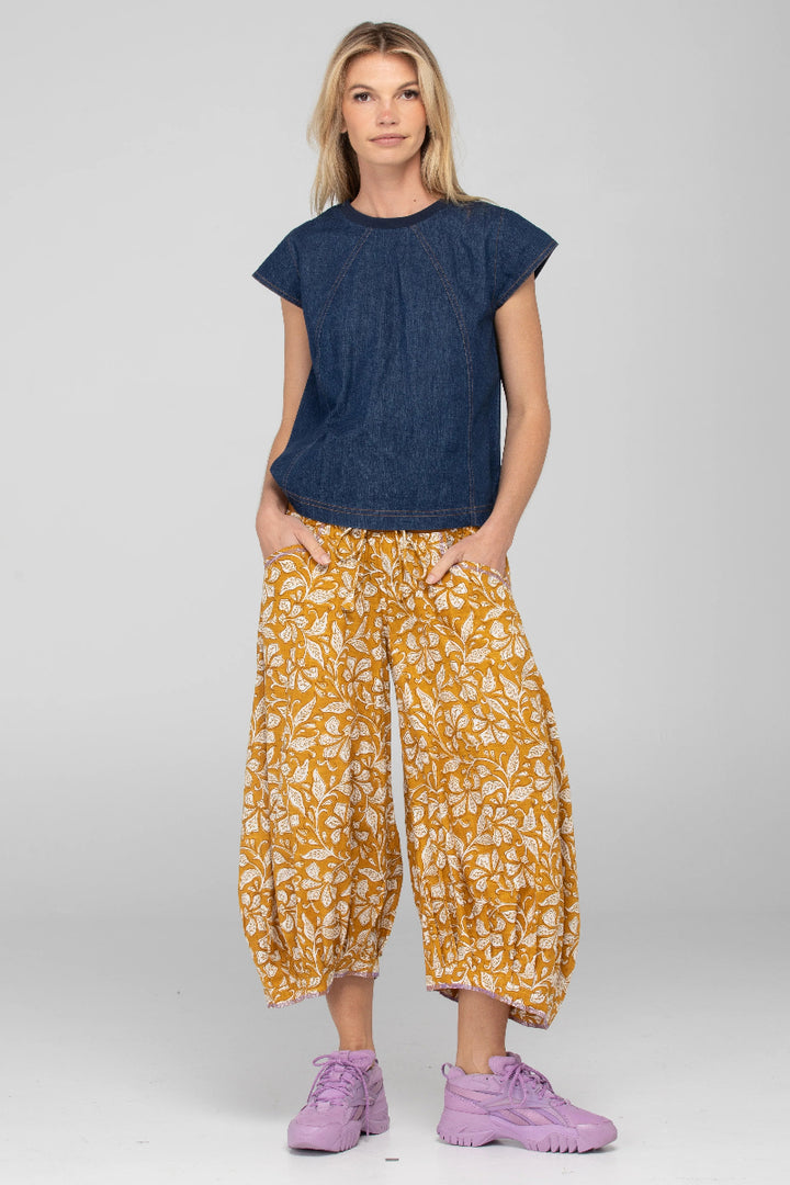 Woman wearing a blue top and yellow patterned pants on a white background