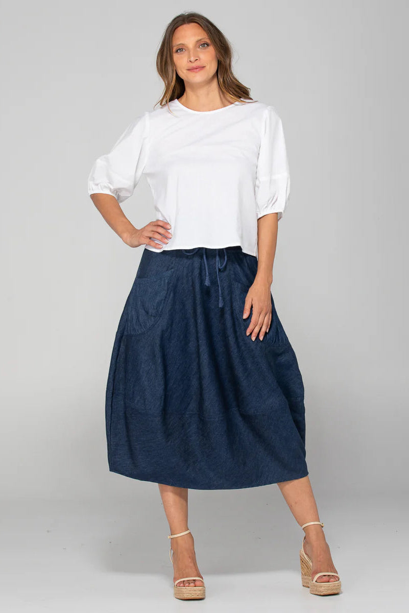 Woman wearing a white blouse and navy blue skirt on a gray background