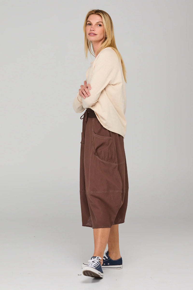 Woman wearing a beige sweater and brown cargo pants on a white background