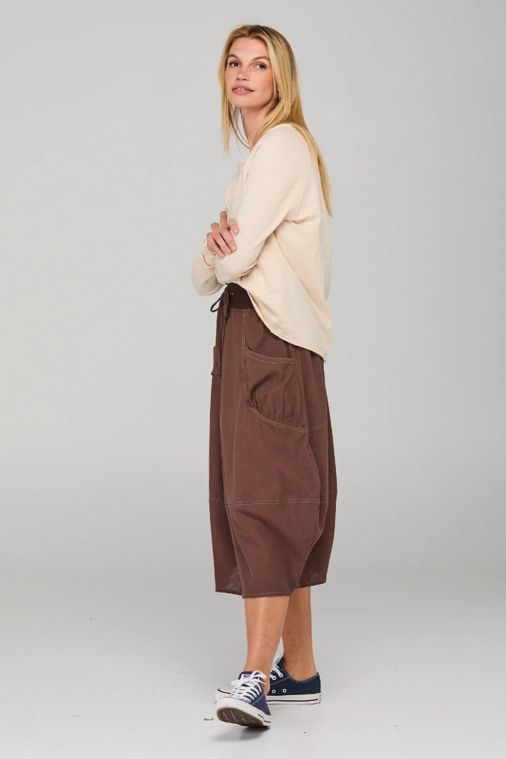 Woman wearing a beige sweater and brown cargo pants on a white background