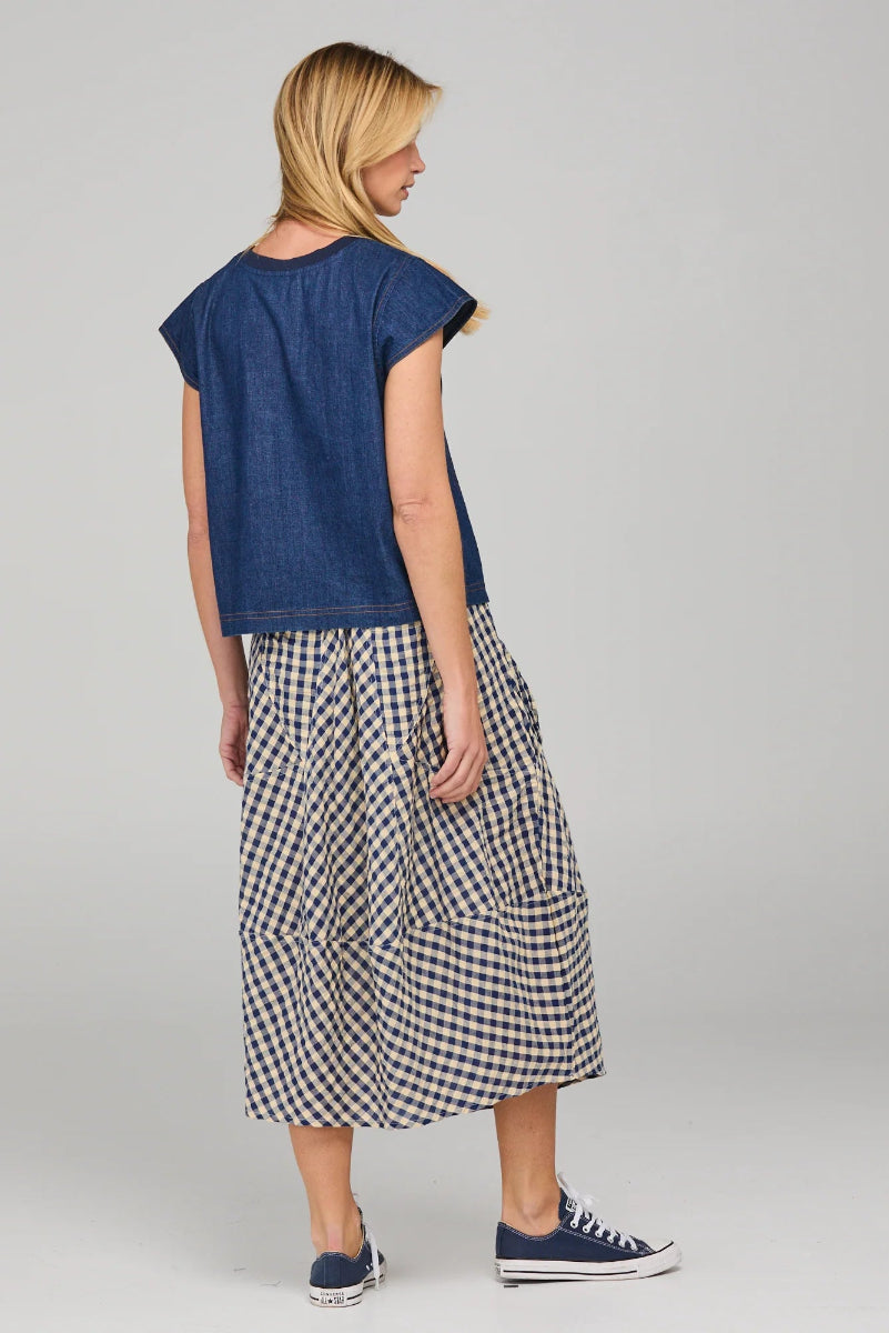 Woman wearing a blue top and checkered skirt on a gray background