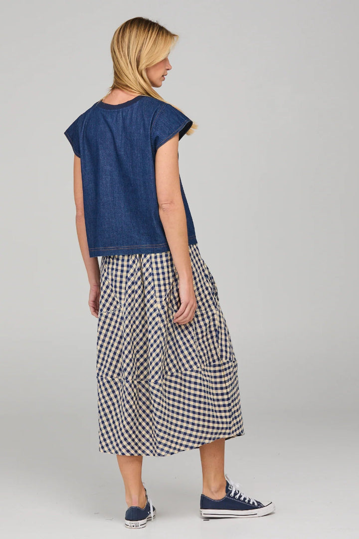 Woman wearing a blue top and checkered skirt on a gray background