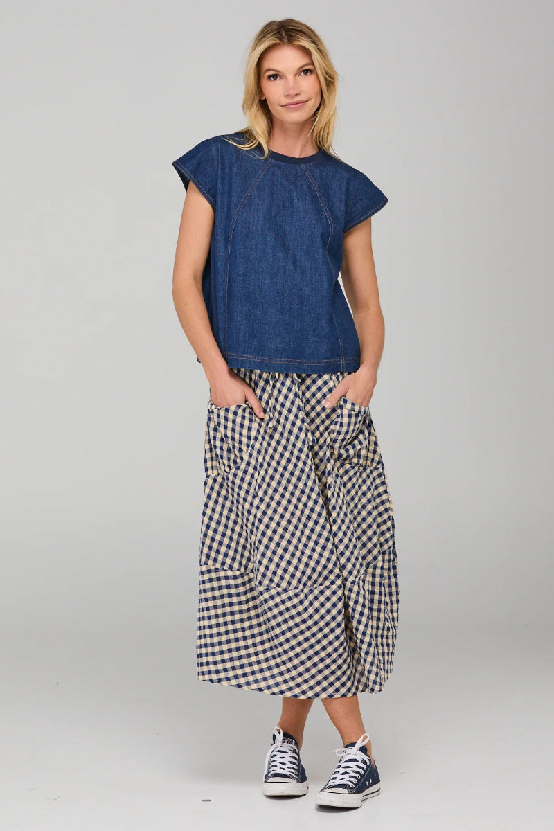 Woman wearing a blue top and checkered skirt on a gray background