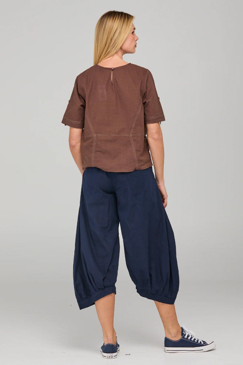 Person wearing a brown top and navy blue pants on a plain background