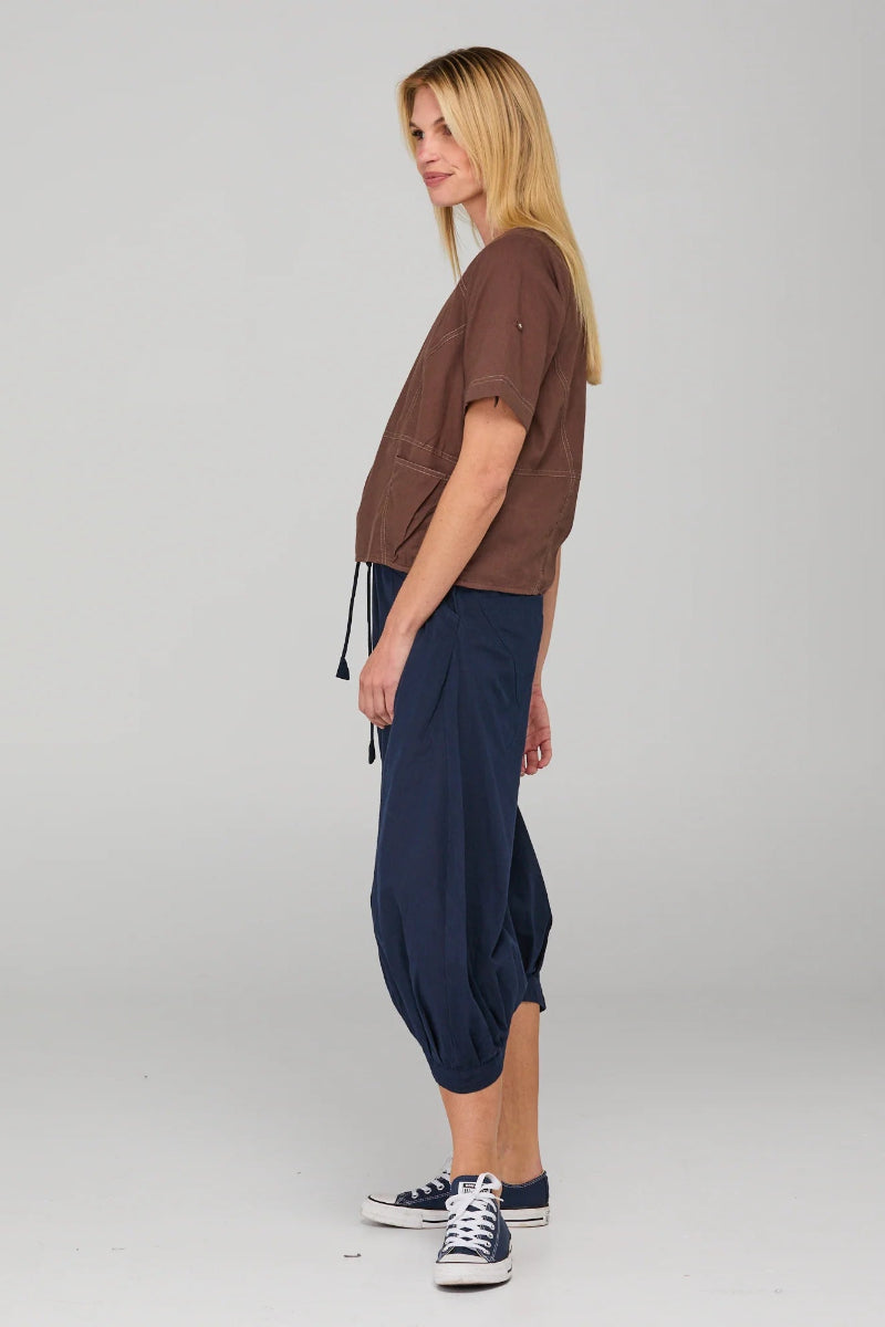 Woman wearing a brown top and navy blue pants on a white background