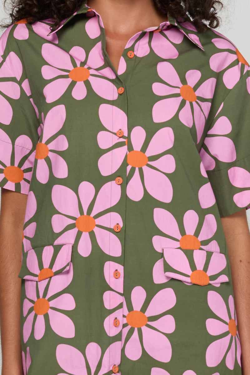 Person wearing a shirt with a floral pattern on a plain background