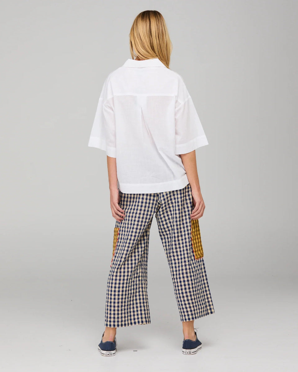 Person wearing a white shirt and checkered pants with yellow accents on a gray background