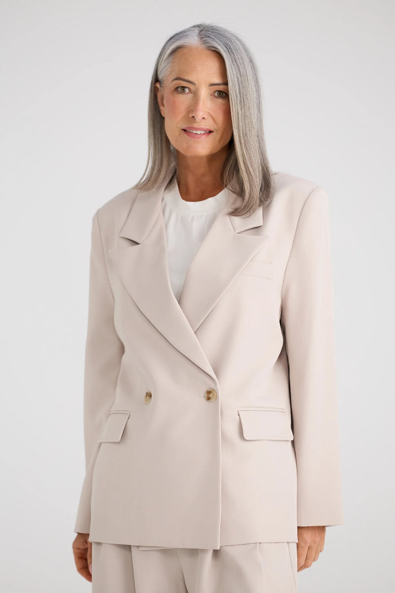 Woman wearing a beige suit with a white background